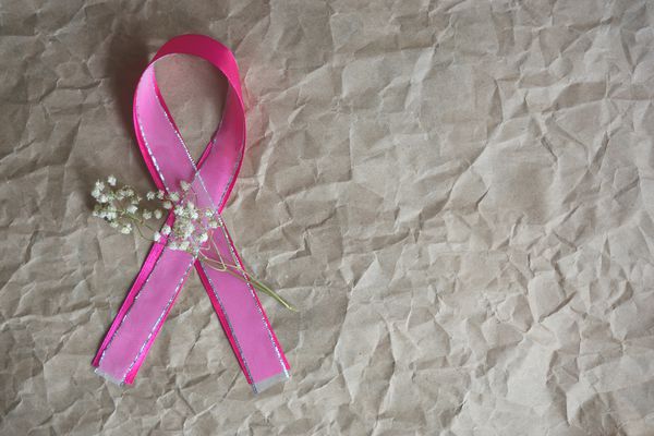 عکس افقی برای ماه آگاهی ملی سرطان پستان با روبان های تزئینی صورتی با شاخه گل های کوچک سفید روی کاغذ کرافت