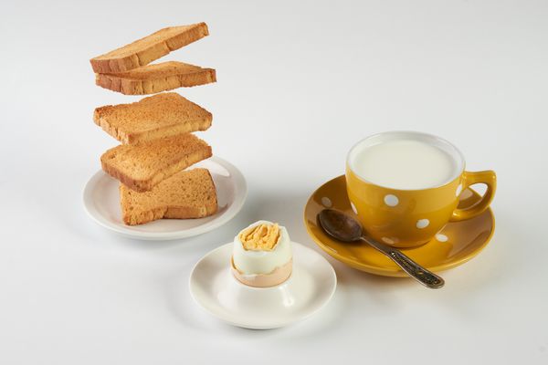 پرواز نان تست برای صبحانه و فنجان شیر تازه با تخم مرغ در زمینه سفید مفهوم غذای جایگزین مفهوم غذای گیاهی سالم
