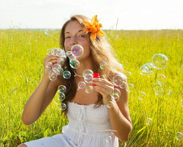 دختر با لباس سفید در طول تابستان حباب صابون درست می کند