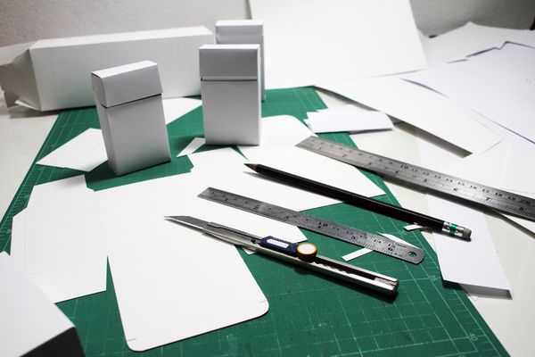 جعبه قالب بسته بندی لوازم آرایشی و بهداشتی محصول و کارگاه طراحی و توسعه ساختار روی تخته برش با ابزار طراحی صنایع دستی با تجهیزاتی مانند چاقوی برش خط کش مداد