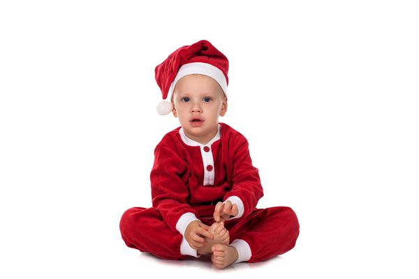 کودک کوچک در کت و شلوار سانتا می خندد و لبخند می زند کودک در لباس کریسمس قرمز جدا شده در پس زمینه سفید