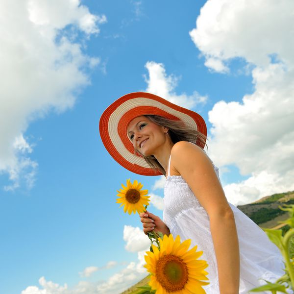زن جوان در تابستان آفتابگردان در حال شکوفه
