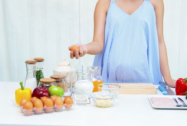 زن حامله ای که در وعده های غذایی در آشپزخانه وعده های غذایی سالم را در دوران بارداری آماده می کند