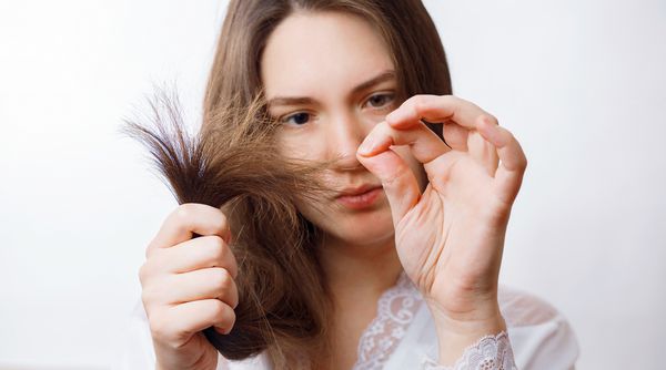 زن به نکات مو آسیب دیده موهای تقسیم شده دختر به موهای خود نگاه می کند
