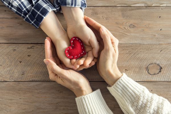 قلب قرمز در دست کودک و زن بیش از پس زمینه چوبی فضای کپی کنید مفهوم مهربانی خانواده عشق و نیکوکاری دست ساز یا مادر و هدیه روزانه
