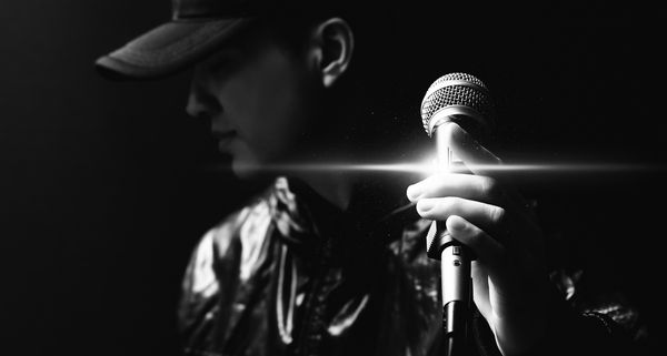 پرتره خواننده خوش تیپ آسیایی که روی میکروفون سیاه و سفید قرار دارد