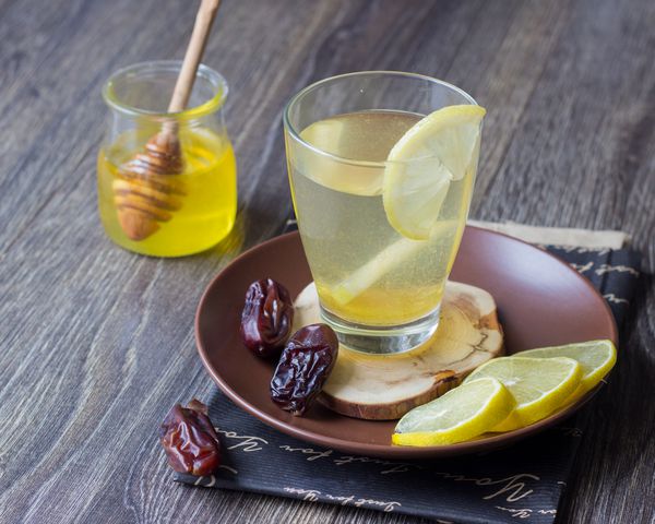 فنجان چای گیاهی را با برش های لیمو و عسل در زمینه قهوه ای