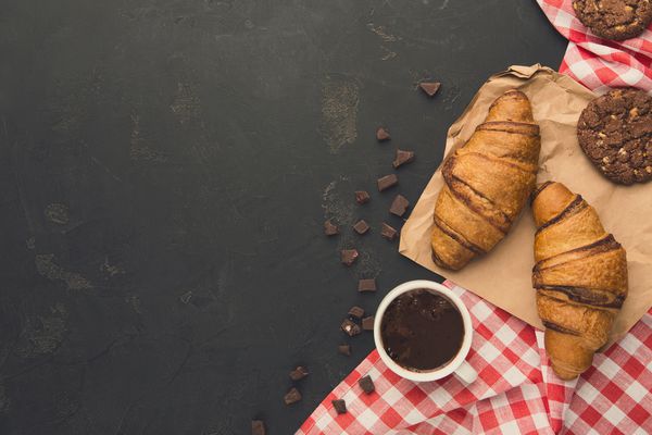 كروسانسان فرانسوی و زمینه قهوه نمای برتر در شیرینی تازه پخته شده و ادویه جات ترشی جات بر روی چوب روستایی با فضای کپی مفهوم صبحانه خوشمزه مدل سازی برای دستور غذا یا کتاب آشپزی