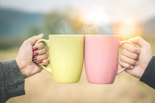 دست های زوج صبح امروز در فضای باز لیوان قهوه دوستان از نوشیدن کنار هم برای دو فنجان لذت می برند