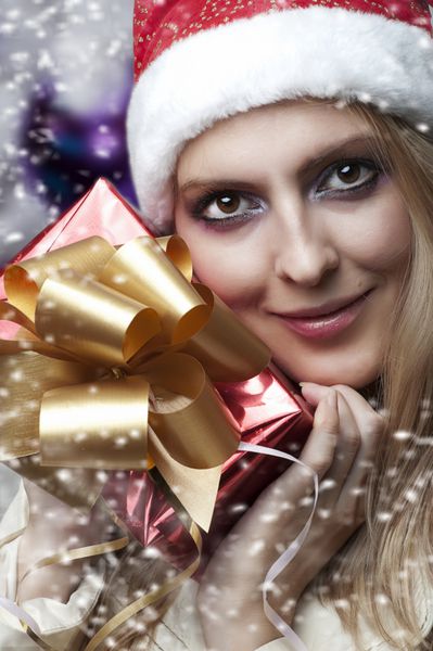 مفهوم کریسمس پرتره زیبایی مدل زن هدیه برگزاری دست در دست و لبخند در مورد درخت کریسمس در کلاه بابا نوئل