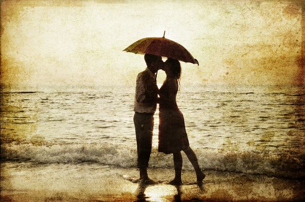 بوسیدن زن و شوهر در زیر چتر در ساحل در غروب آفتاب عکسی به روش تصاویر قدیمی