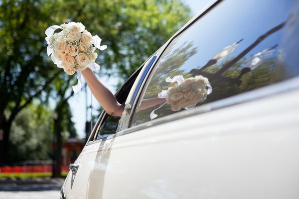 دست عروس با دسته گل از ماشین نگه می دارد
