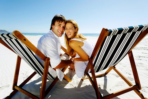 یک زن و شوهر شاد واقعی در تعطیلات تابستانی در ساحل برای یک پرتره در کنار هم قرار می گیرند با خنده و لبخند با شادی خالص