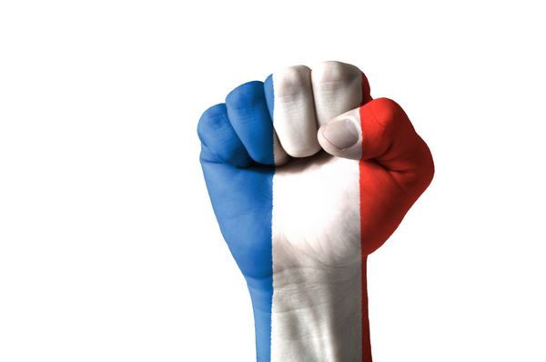 تصویر کم کلید از یک مشت که در رنگ های پرچم فرانسه قرار گرفته است