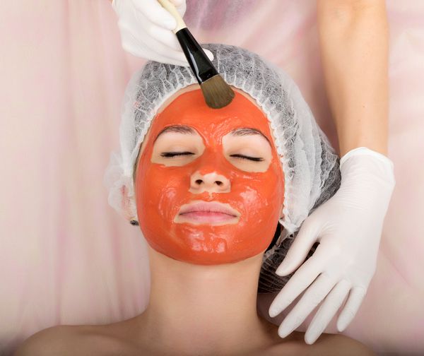 متخصص زیبایی ماسک زیبایی را بر روی صورت بیمار مشاوره حرفه ای انجام می دهد