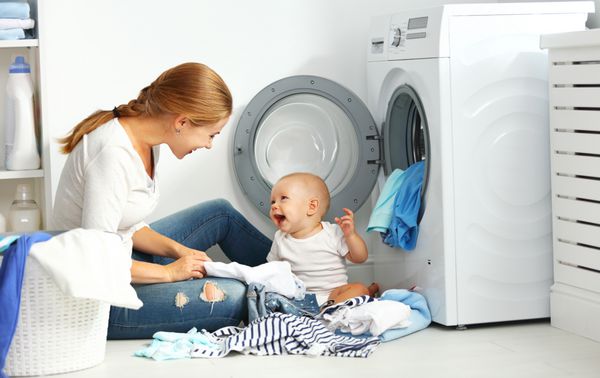 یک زن خانه دار با یک کودک لباس را داخل لباسشویی بکشید