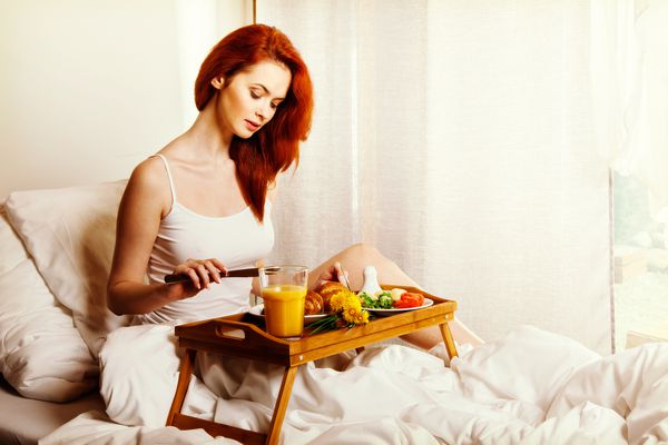 زن جوان صبحانه صبحانه را در رختخواب می خورد