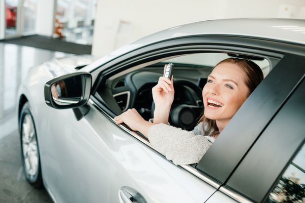 زن جوان کلید نگه داشتن در حالی که در ماشین جدید نشسته است