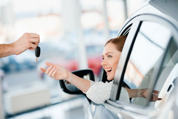 فروشنده با دادن کلید زن جوان که در اتومبیل جدیدی نشسته است