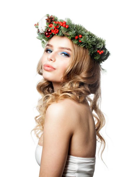 کریسمس زیبا زنانه با پوشیدن کریسمس یا دکوراسیون سال نو با گل های درخت کریسمس و توپ شیشه ای مدل مد با آرایش و مو مجعد بلوند جدا شده در زمینه سفید