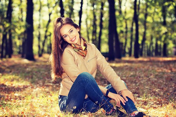 دختر جوانی که در مناظر پاییزی لبخند می زند
