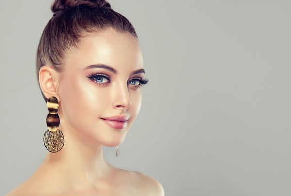 دختر مدل زیبا با مانیکور صورتی روی ناخن ها آرایش و لوازم آرایشی مد جواهرات گوشواره بزرگ و درخشان طلایی