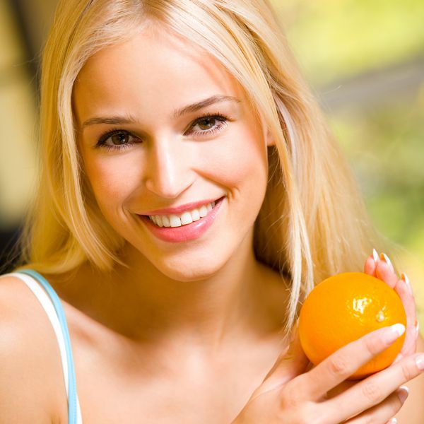 زن خندان جوان با نارنجی