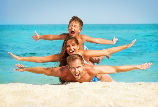 خانواده جوان مبارک با بچه کوچک در تفریح ​​ساحل
