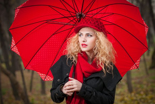 دختر جوان شیک و زیبا با چتر قرمز کلاه قرمز و