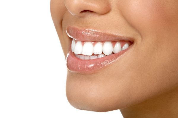 دندان های زن جوان زیبا با زمینه سفید مجزا شده است