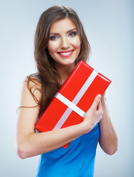 زن لبخند جوان جعبه گیت قرمز را با روبان سفید نگه می دارد