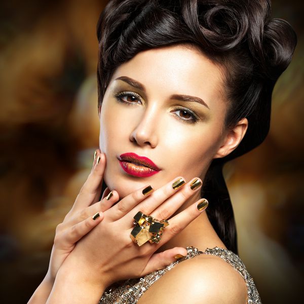زن زیبایی با ناخن های طلائی و لب های قرمز