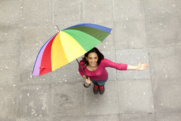 زن خندان مبارک که زیر چترهای چند رنگ پنهان شده است