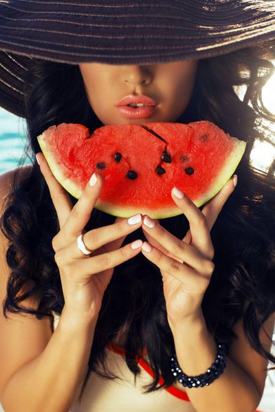 دختر با موهای تیره که هندوانه می خورد
