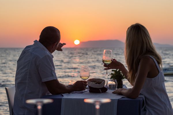 زن و شوهر خورشید در رستوران ساحل در غروب آفتاب