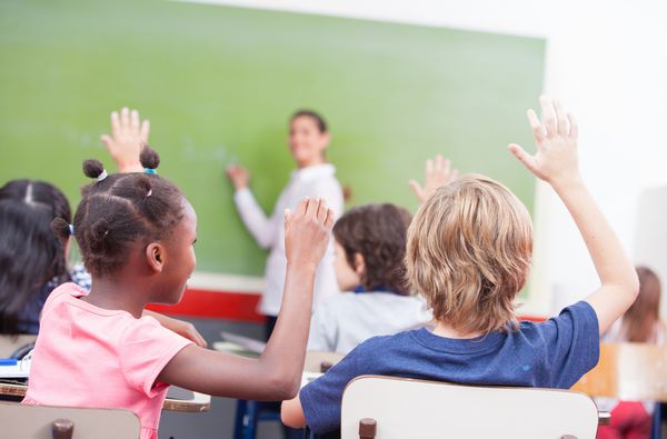 پرتره کودکان دست خود را در کلاس چند قومی بلند کرد
