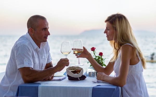 زن و شوهر در رستوران دریا در غروب آفتاب