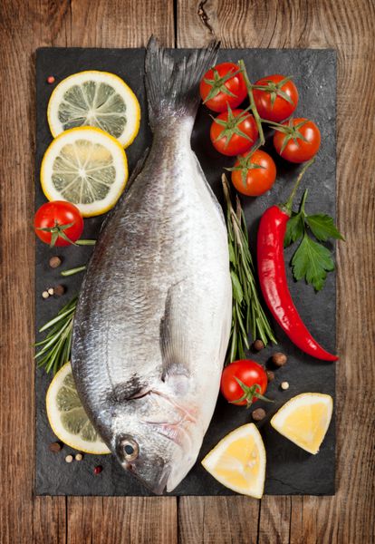 ماهی تازه لیمو ادویه جات ترشی جات و گوجه فرنگی گیلاس را روی تخته سنگی قرار دهید