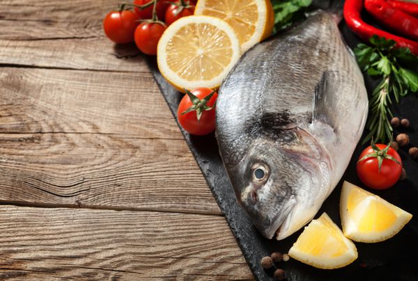 ماهی تازه لیمو ادویه جات ترشی جات و گوجه فرنگی گیلاس را روی تخته سنگی قرار دهید