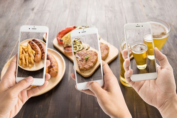دوستان با استفاده از تلفن های هوشمند برای گرفتن عکس از کالباس و گوشت خوک