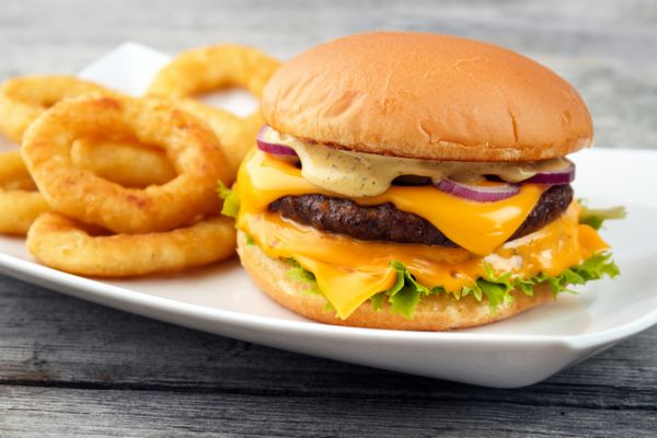 Cheeseburger با حلقه های پیاز سرخ شده عمیق سرو می شود