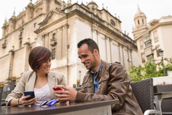 زن و شوهر جوان در تراس بار با تلفن های هوشمند