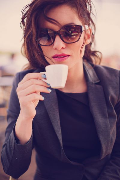 زن جوان در کافه قهوه می نوشد