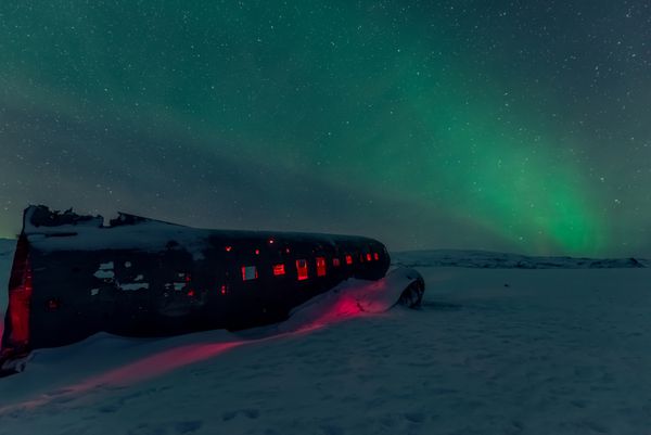 چراغ های شمالی بر فراز هواپیما در ساحل سیاه ویک ایسلند