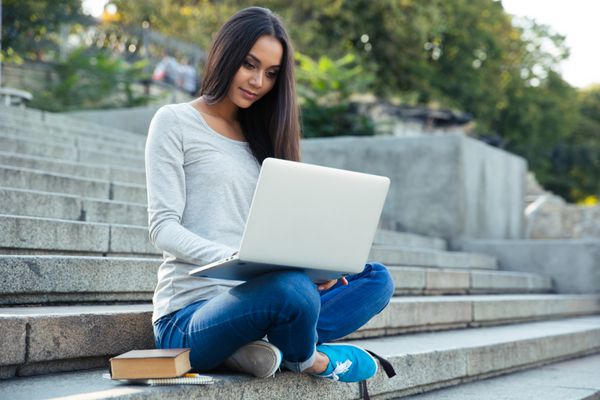 دانشجوی دختر با استفاده از رایانه لپ تاپ در فضای باز