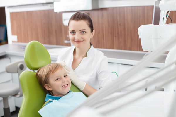 دندانپزشک زن شاد با کودک کوچک کار می کند