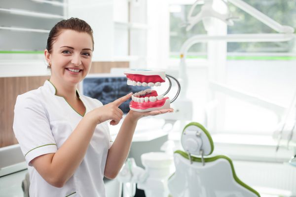 پزشک زن جذاب دندانپزشکی در حال انجام پروتزهای دندانی است