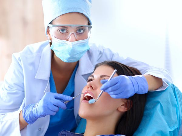دندانپزشک زن که در دندان بیماران خود کار می کند