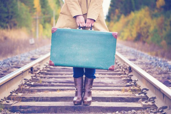 زن زیبا با چمدانی که با راه آهن مسافرت می کند
