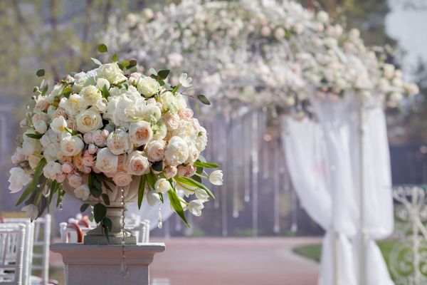 دسته گل زیبا از گل رز در گلدان بر روی زمینه قوس عروسی مجموعه زیبایی برای مراسم عروسی